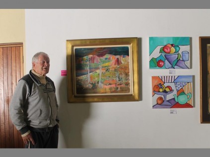 Colin Sutcliffe and a painting by Catherine Paynter. Sutcliffe owns and manages the gallery