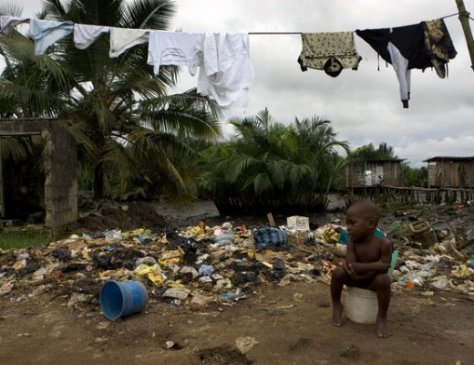 07 Oct 2005, Port Harcourt, Nigeria --- A small child uses a dirty plastic bucket as a toilet in Njemanze, a slum community along the waterfront in Port Harcourt, Nigeria. Areas like this are hotbeds of gang violence and extreme poverty that exemplify the lack of development and support for the local communities of the oil producing Niger Delta. This community has been the scene of violence in recent years between "cults', or gangs supported by the government. --- Image by © Ed Kashi/VII/Corbis